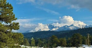 A mountain range with snow-capped peaks, a clear sky, and a forested foreground. - Woodland Park Home with Direct Views of Pikes Peak! (Woodland Park)