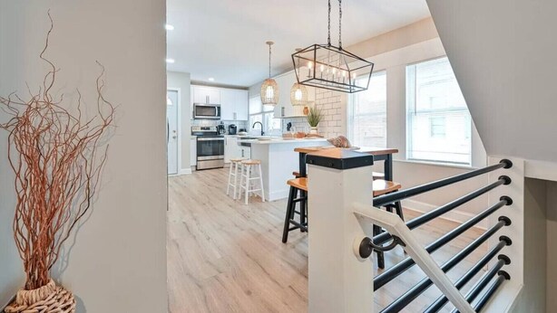 A modern kitchen with a central island, pendant lighting, and a view of the city. - Modern 8BR Ventnor Compound | Patio | BBQ | Games (Ventnor City)