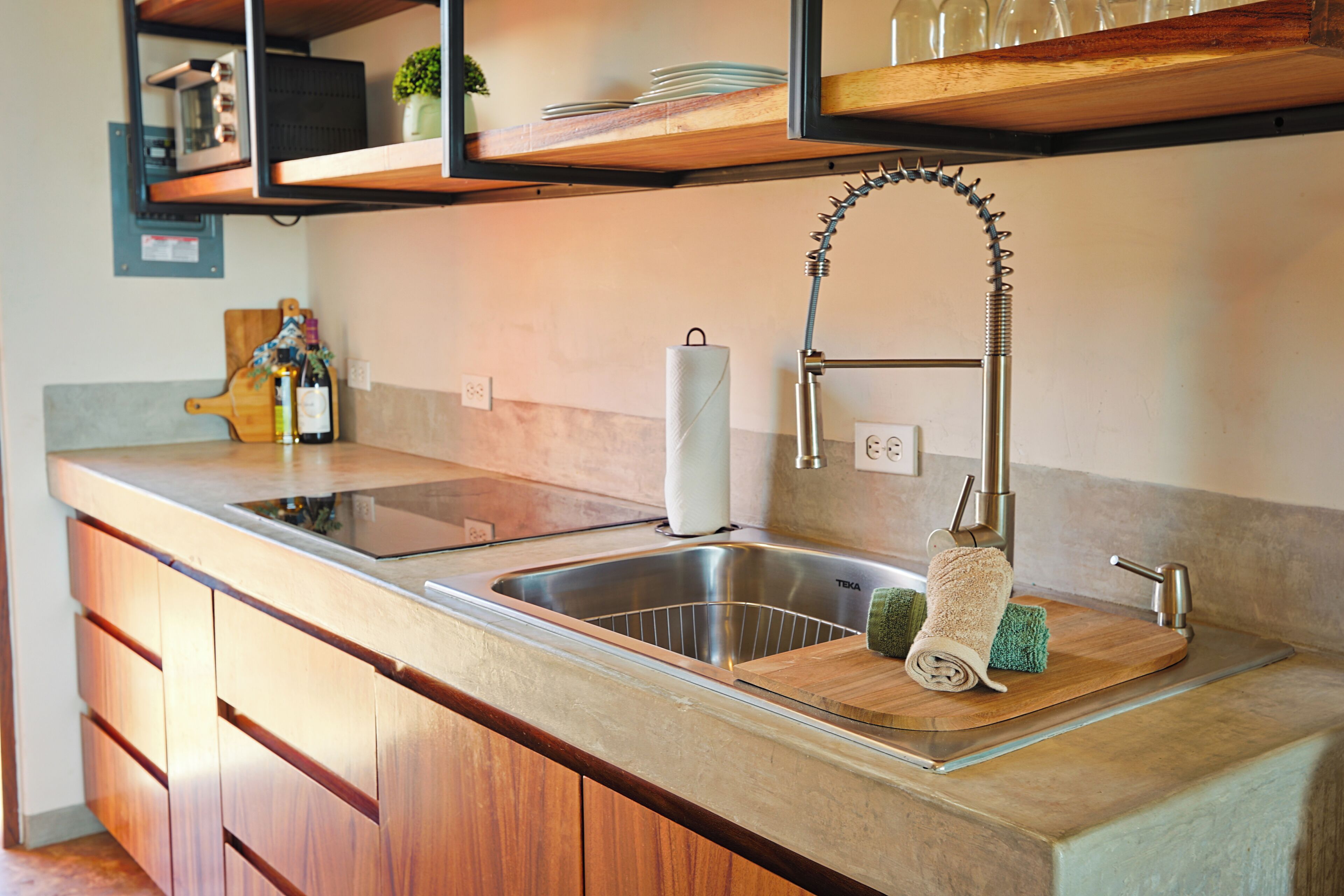 A kitchen with a stainless steel sink, wooden cabinets, a wooden countertop, and a hanging towel rack.