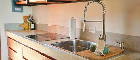 A kitchen with a stainless steel sink, wooden cabinets, a wooden countertop, and a hanging towel rack.