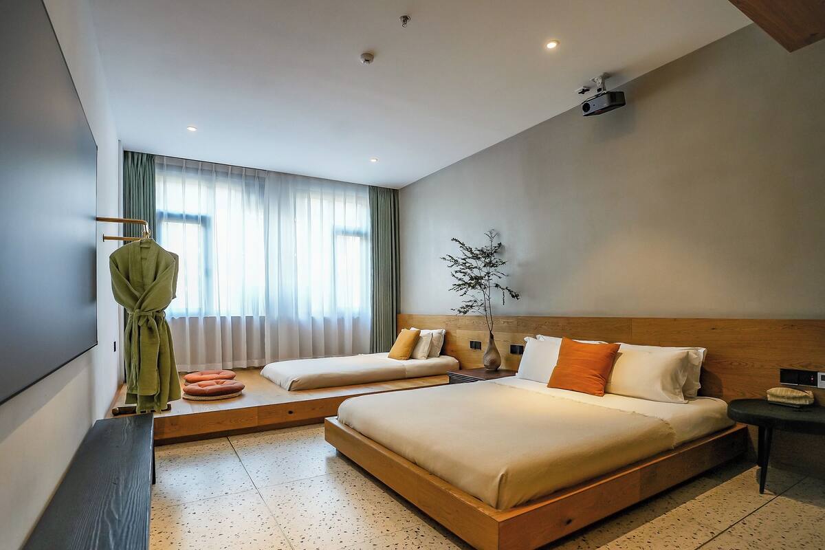Ett modernt hotellrum med en stor säng, en sittgrupp, en TV och en växt.