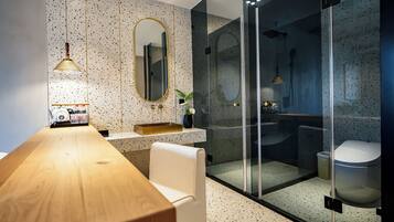 Un baño moderno con tocador de madera, un espejo grande y cabina de ducha con paredes de vidrio.