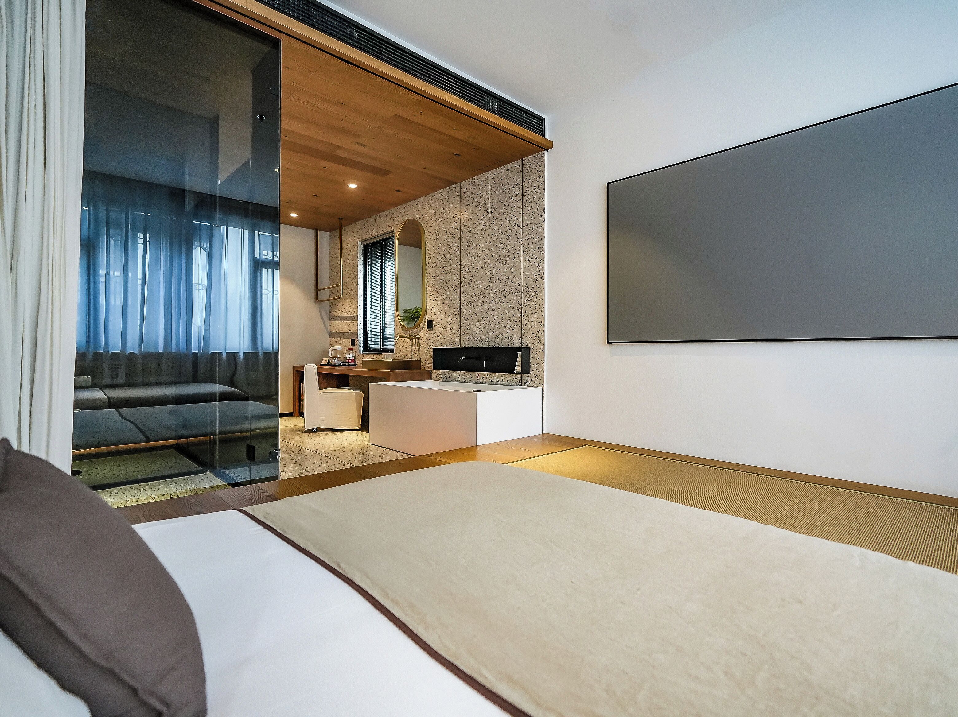 Un dormitorio moderno con cama, escritorio, espejo y televisor.