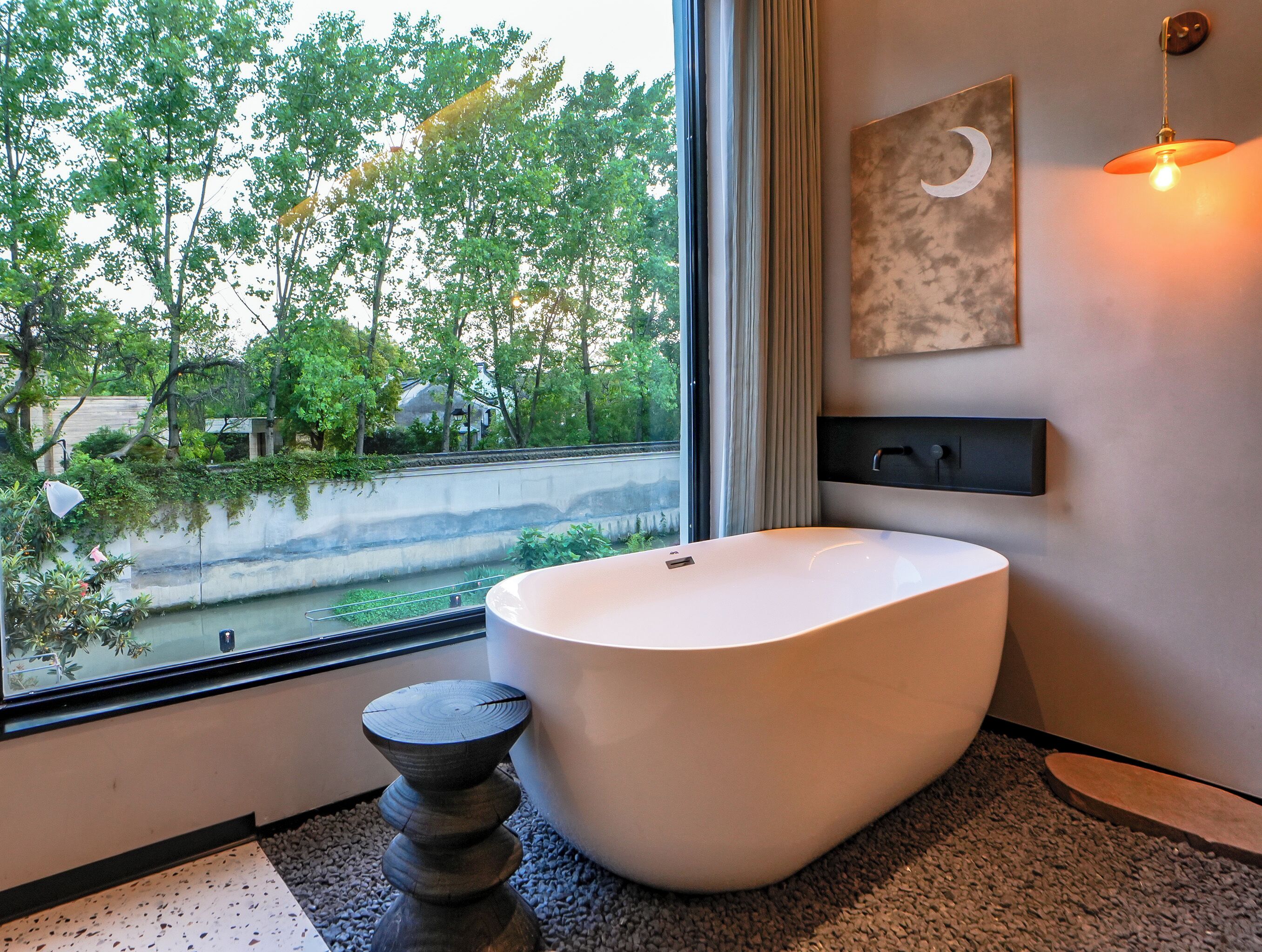 Un bagno moderno con una vasca da bagno spaziosa, una finestra vista su un paesaggio verde e un design minimalista.