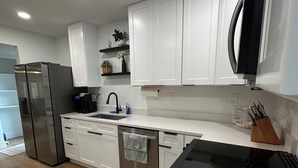 Une cuisine moderne avec des meubles blancs, des appareils en acier inoxydable et une cuisinière noire.