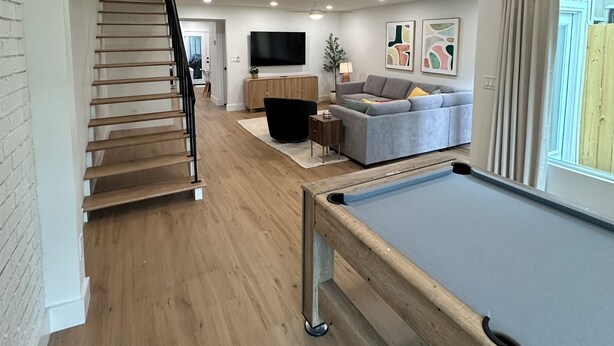 Un intérieur en bois comprenant une table de billard, un canapé, un téléviseur et un escalier.