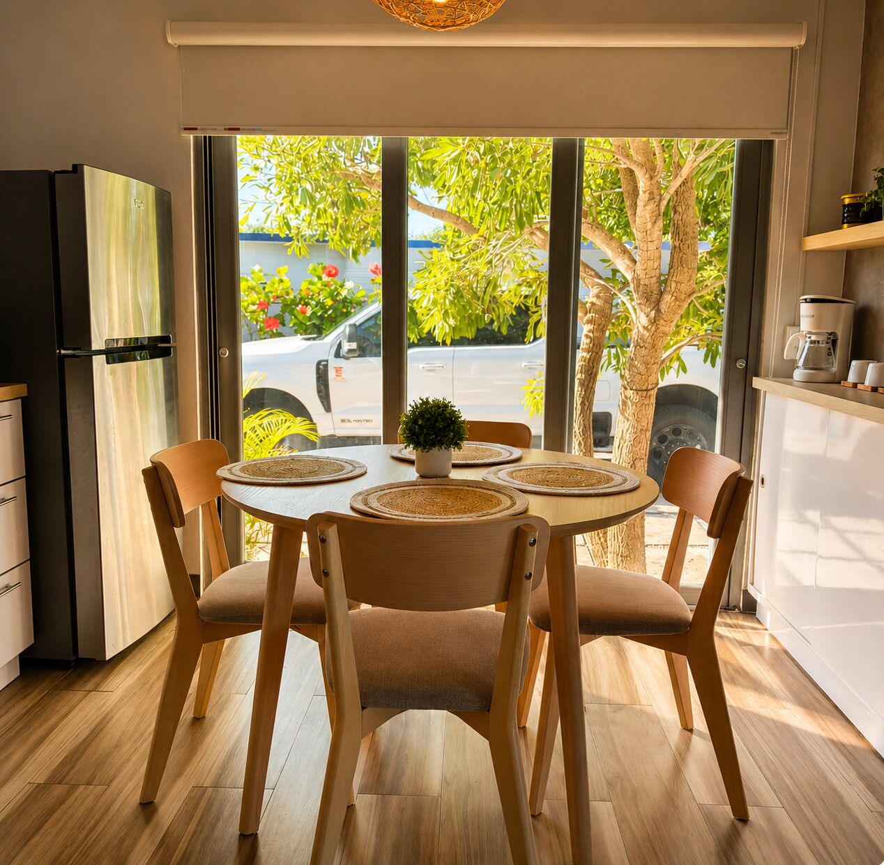Uma cozinha moderna com uma mesa de jantar, cadeiras, uma televisão e uma máquina de café.