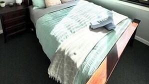 A bedroom with a bed, a nightstand, a window, and a painting on the wall. - Collopy Escape Mansfield (Mansfield)