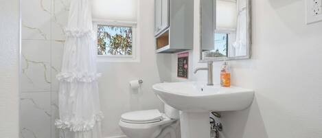 A bathroom with a toilet, sink, and a shower curtain.