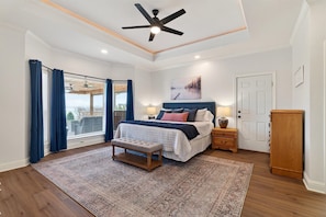 A bedroom with a bed, a bench, a ceiling fan, a nightstand, a wooden cabinet, and a window with curtains.
