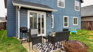 A blue house with a patio area featuring a grill, chairs, and a table. - 5 BR Family Fun, Sleep 12, Climbing Wall & Games (Meridian)