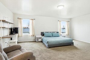 A bedroom with a bed, a desk, a chair, and a window.
