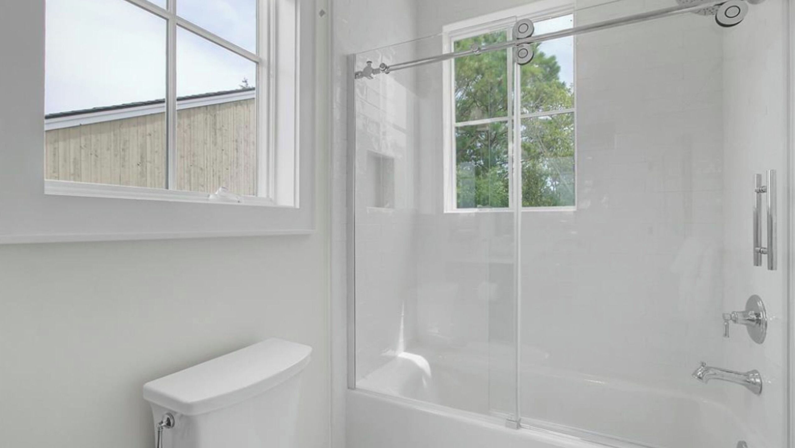 A bathroom with a toilet, a bathtub, and a glass shower enclosure.