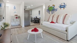 A living room with a white sofa, a small white table, and a red object on the table.