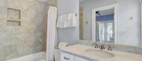 Une salle de bain équipée d’une baignoire, d’une douche, d’un lavabo avec un miroir et de toilettes.