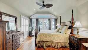A bedroom with a large bed, a ceiling fan, a dresser, and a window with curtains. - 5 32nd Avenue by Avantstay Gourmet Kitchen Pool Balconies (Isle of Palms)