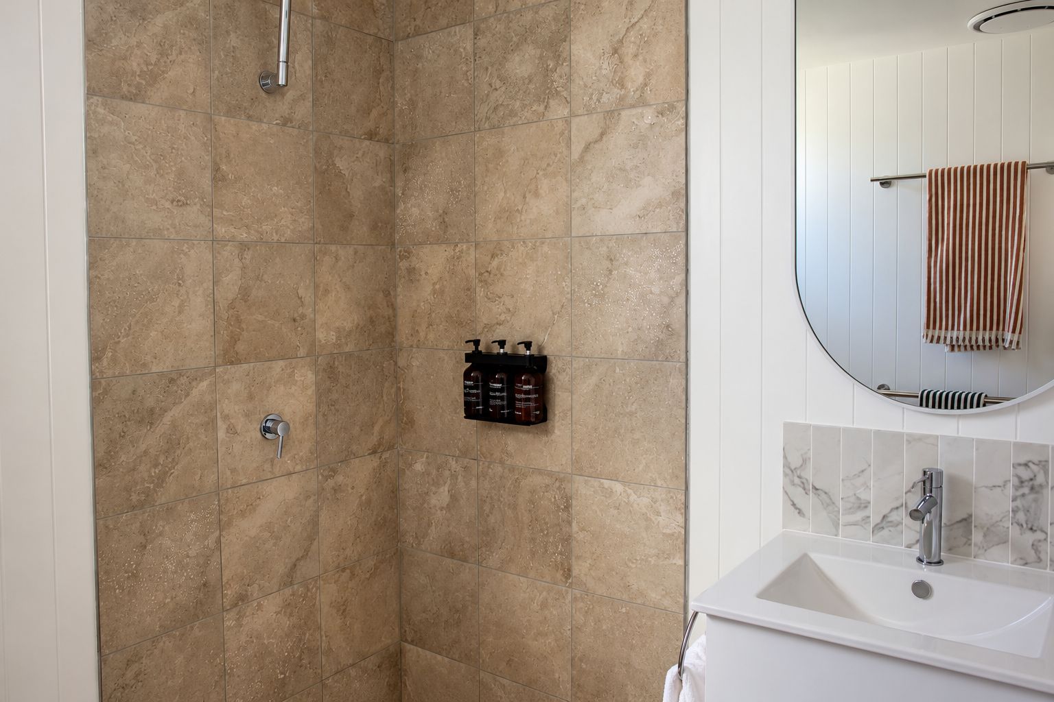 A bathroom with a shower, a sink, and a mirror.