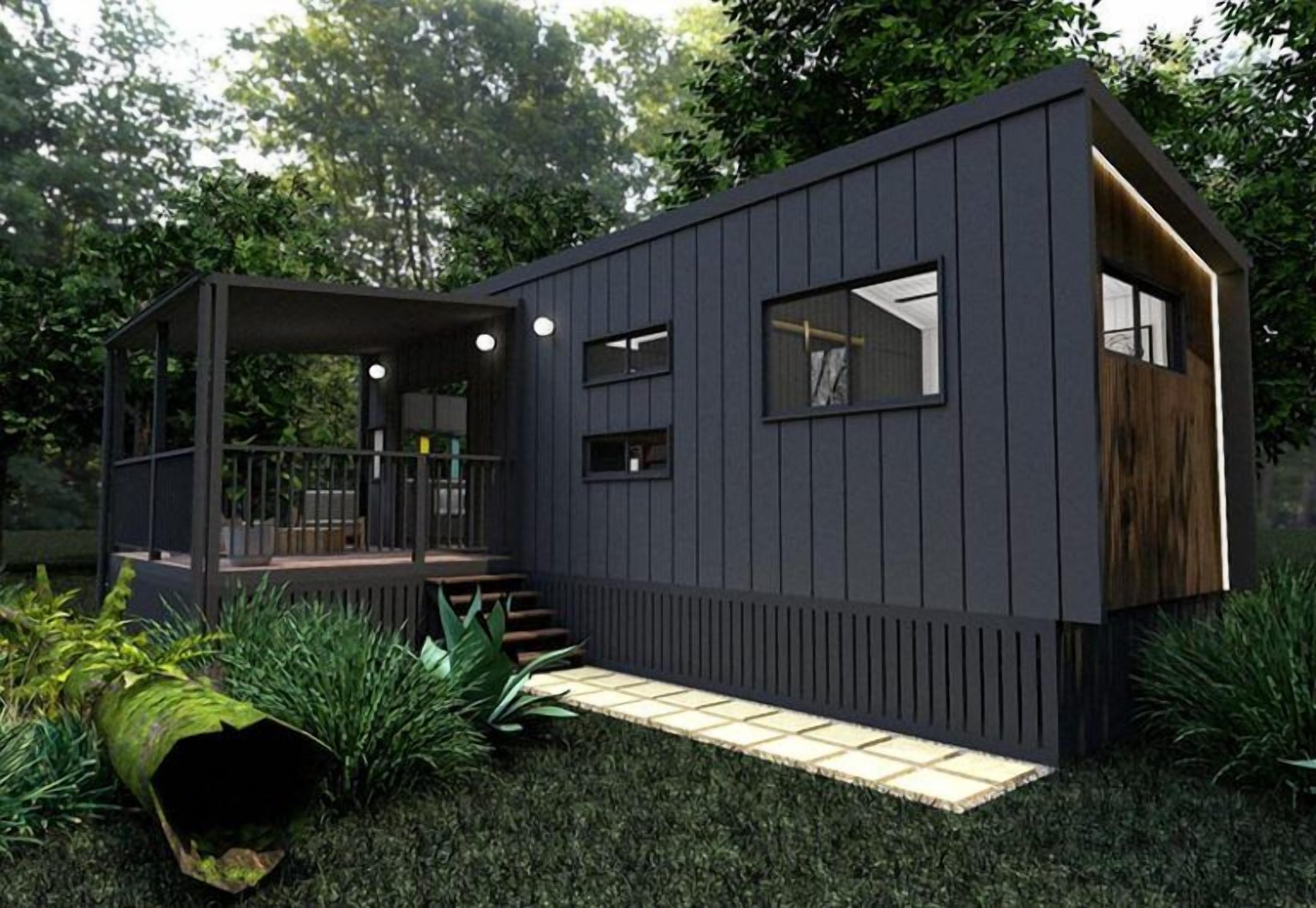 A modern, dark-colored cabin with a wooden deck, a small porch, and a window.