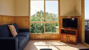 Una stanza con un'ampia finestra, un armadio in legno con un televisore e un divano blu scuro.