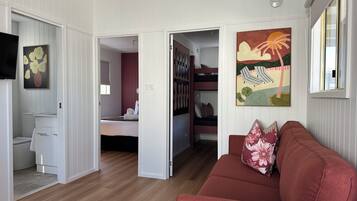 A room with a red sofa, a painting, and a bunk bed with pillows.