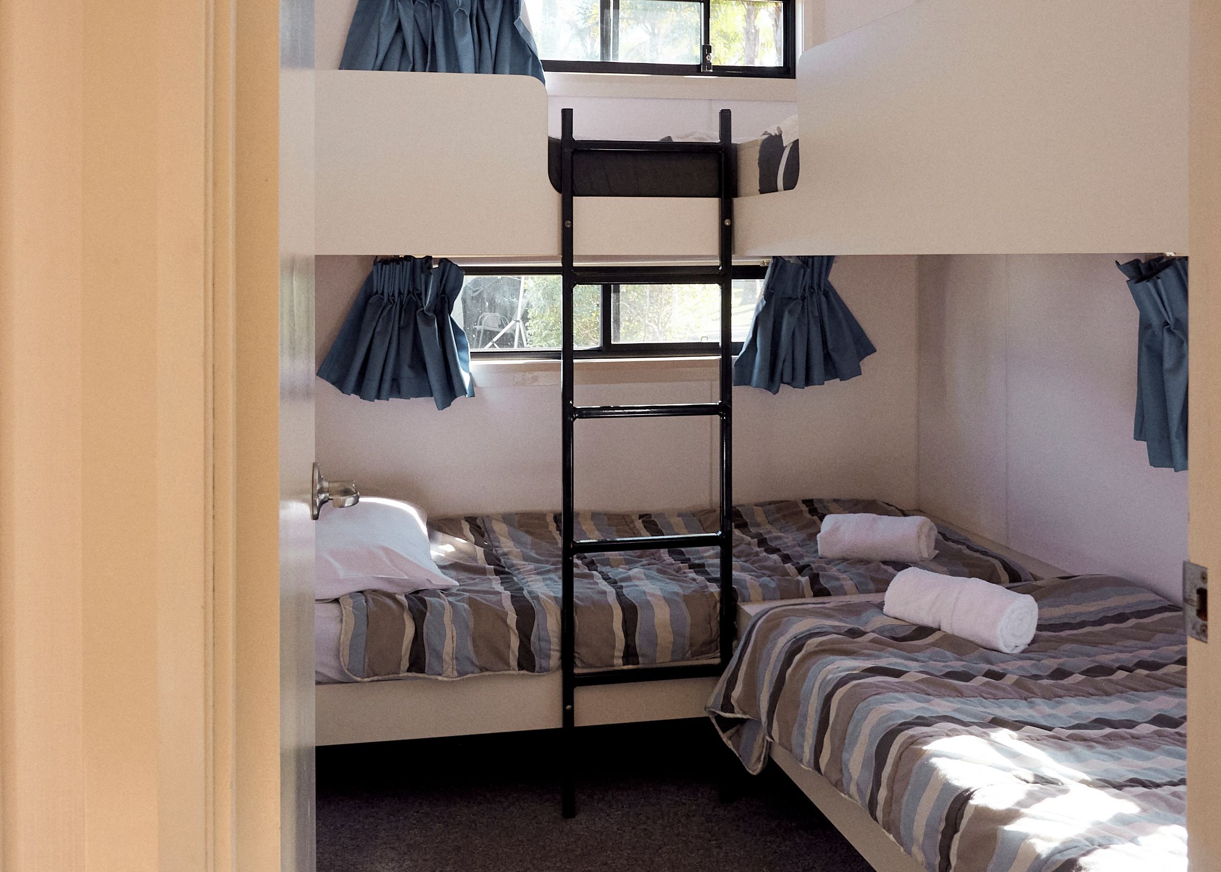 Een slaapkamer met een stapelbed, een raam en gordijnen.