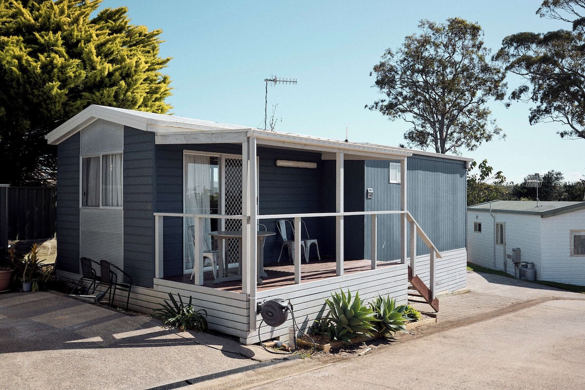 Una casa móvil de una sola planta, pequeña, con un porche, puerta corredera y una pequeña terraza.