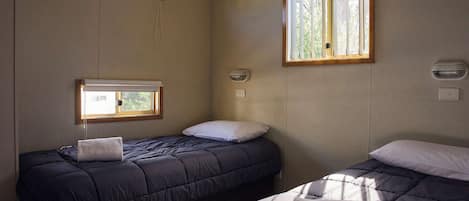 Une chambre avec deux lits, une fenêtre et un luminaire fixé au mur.