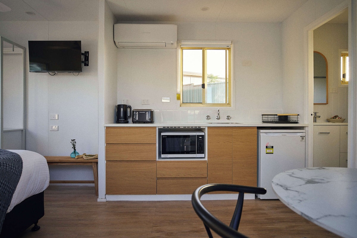 Una cocina compacta equipada con microondas, cafetera y un refrigerador pequeño.