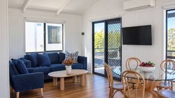 A living room with a blue sofa, a coffee table, and a dining area with chairs and a glass table.