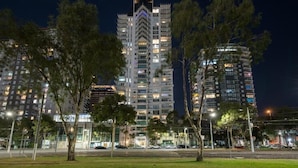 Um edifício alto com vários andares, rodeado por árvores e postes de luz.