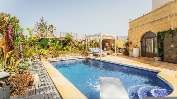 A swimming pool with a lounge area, surrounded by lush greenery and a stone building. - Tal Jordan Complex - Bungalow 3 Frog (Gharb)
