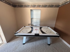 A room with a foosball table, a window, and a door.