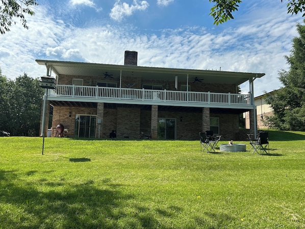 A two-story house with a covered patio, a brick chimney, and a fenced yard.