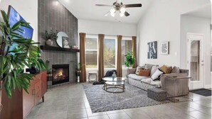 Ein modernes Wohnzimmer mit Kamin, einer Couch, einem Couchtisch und einem Fernseher.