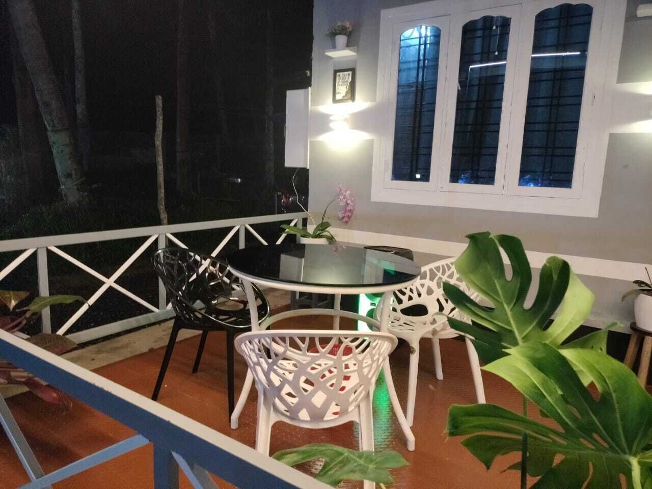 Una terrazza con tavolo e sedie, una pianta in vaso e una finestra con tende.