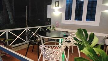 Una terrazza con tavolo e sedie, una pianta in vaso e una finestra con tende.