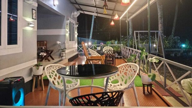 An outdoor seating area with a table and chairs, surrounded by potted plants and a railing.
