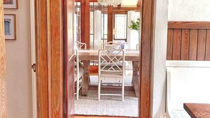 A wooden interior with a dining table, chairs, a chandelier, and a patterned rug. - Pristine Craftsman 1900s Bungalow w Pool & Hot Tub (Savannah)