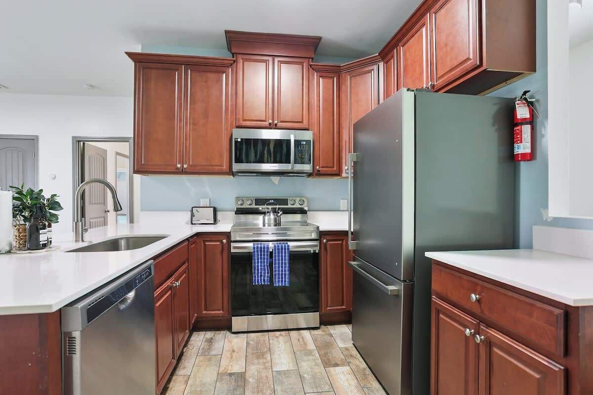 A kitchen with wooden cabinets, stainless steel appliances, and a tiled floor.