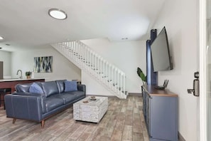 A modern living room with a sofa, coffee table, and a staircase. - Cozy Cottage Near Thunderbolt Marina w Fenced Yard (Thunderbolt)