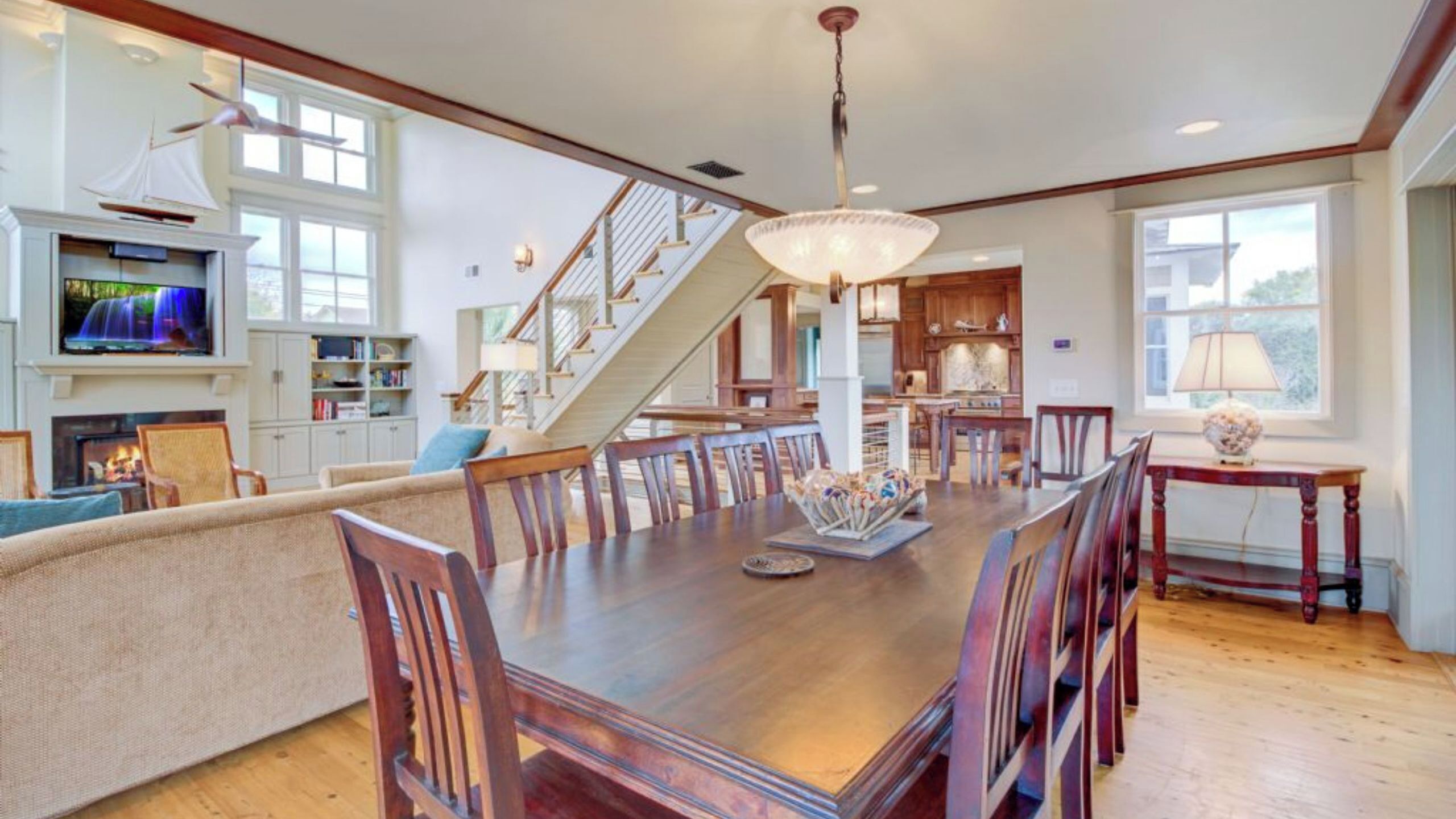 A spacious dining area with a large wooden table, multiple chairs, and a chandelier.