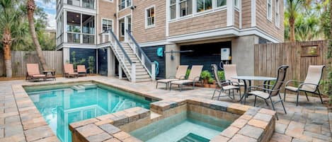 A residential building with a swimming pool, outdoor seating, and a staircase leading to an upper level.