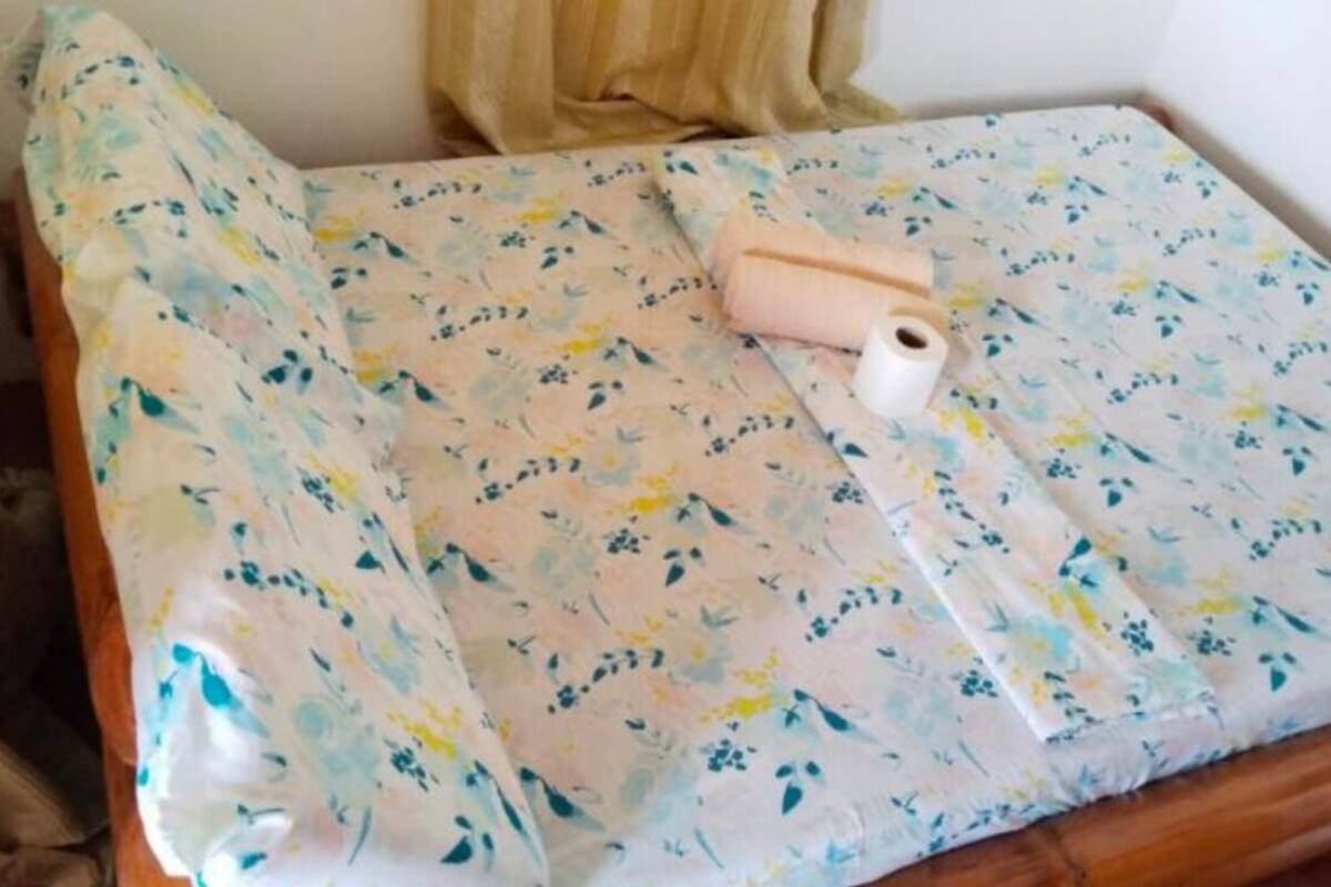 A bed with a floral-patterned bedspread and a rolled-up towel.