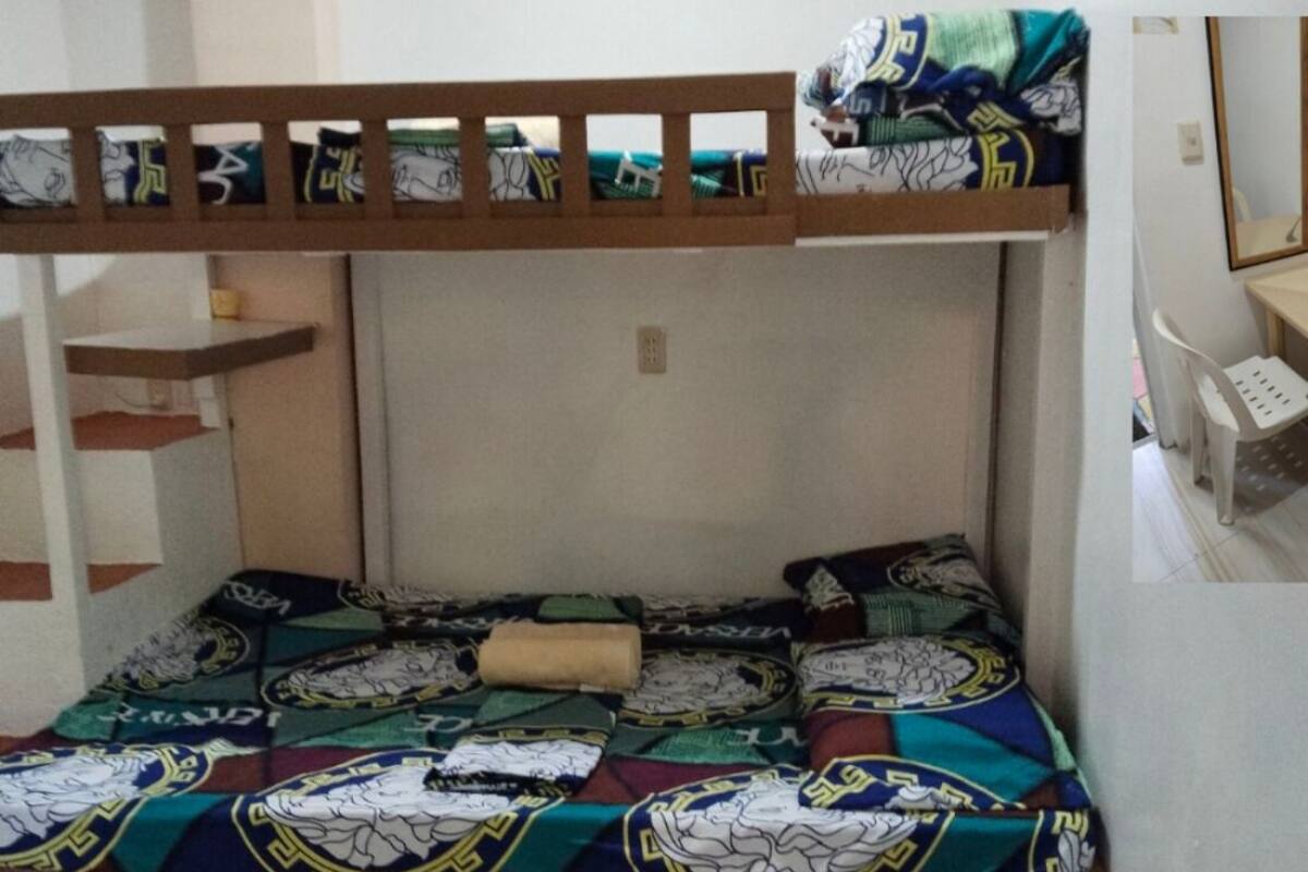A bunk bed with patterned bedding, a wooden headboard, and a small shelf.