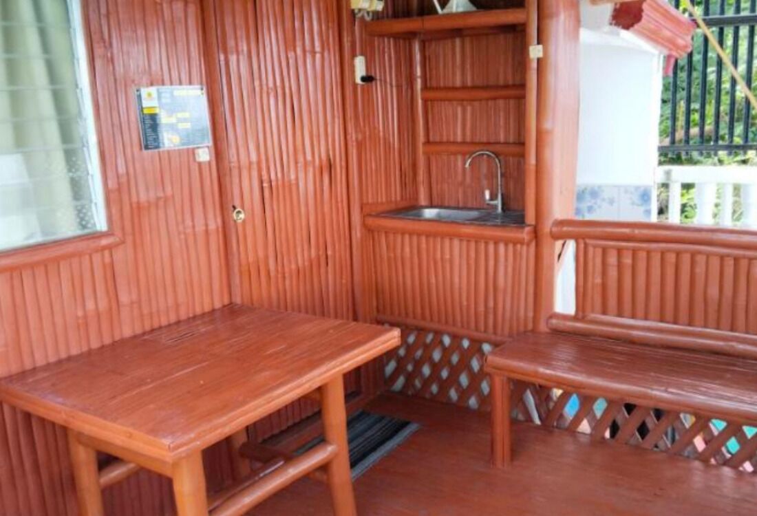 Une pièce en bois avec une table, un banc et un petit lavabo.