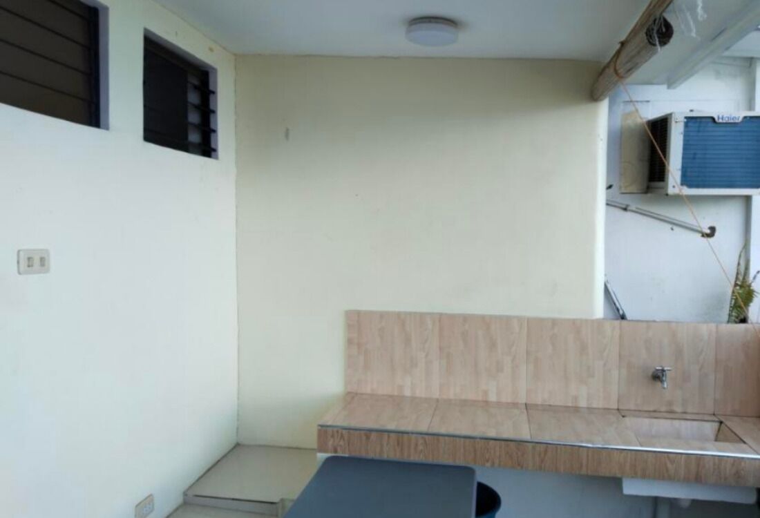 A small, enclosed bathroom with a wooden vanity, a sink, and a shower area.