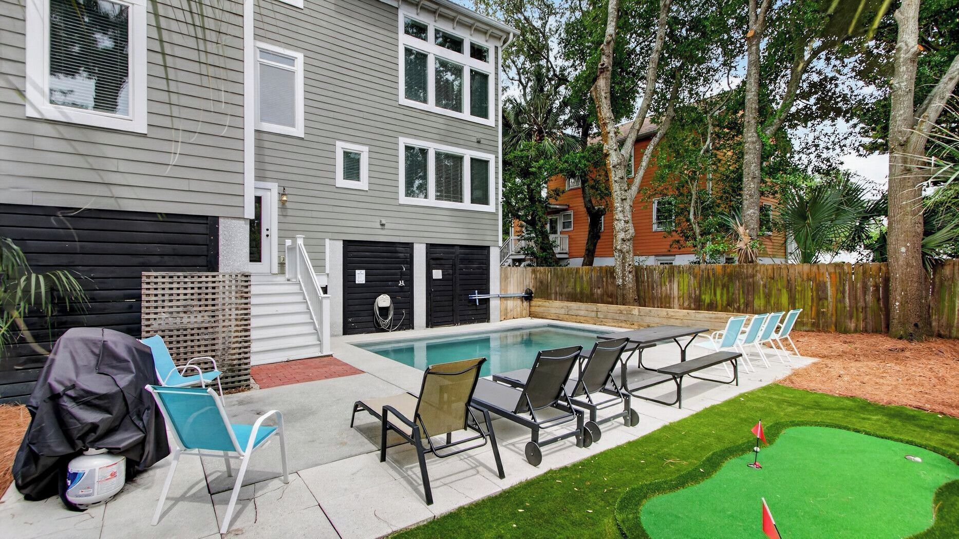 A backyard with a swimming pool, outdoor seating, and a miniature golf course.