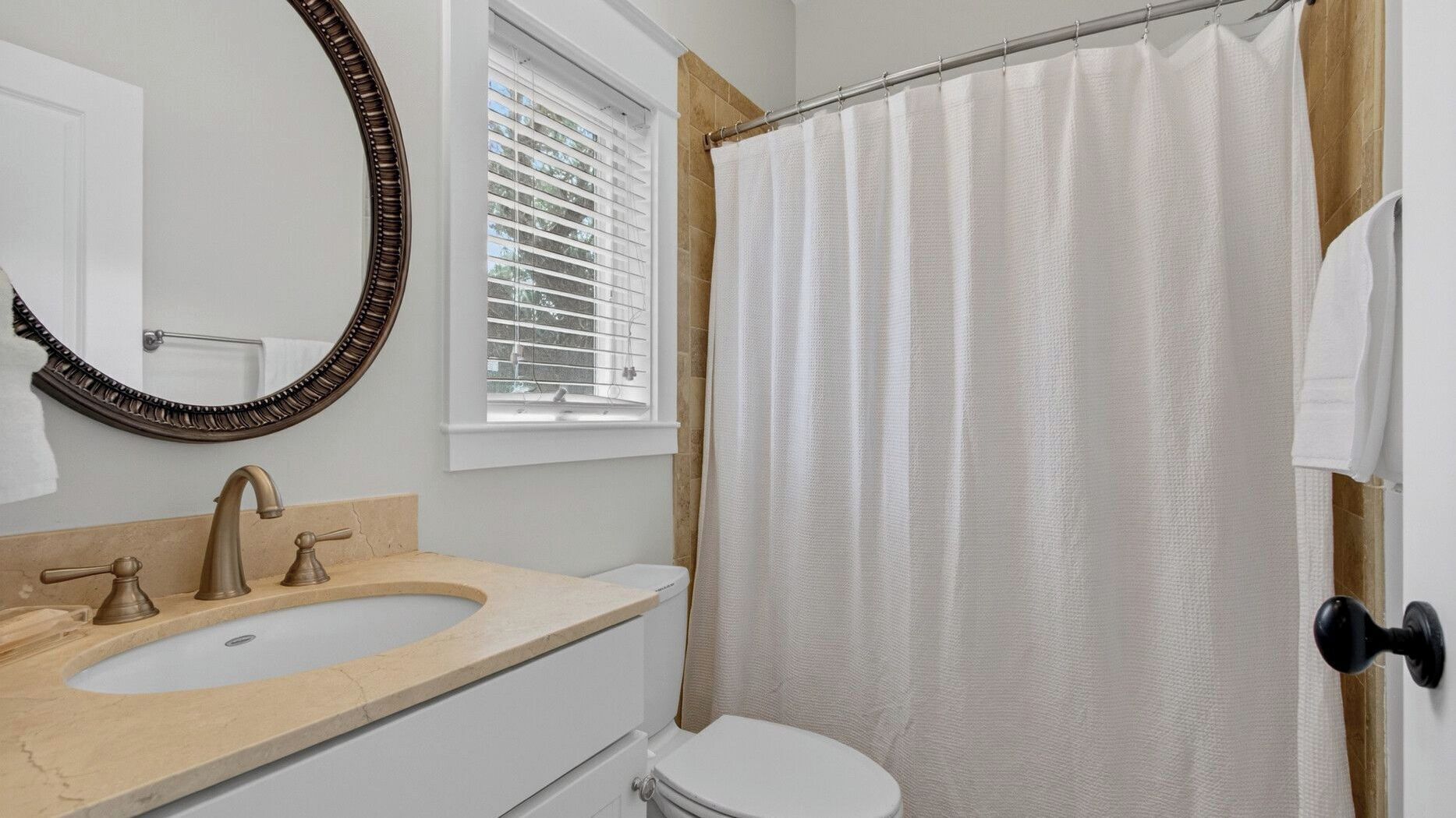 Et badeværelse med vask, toilet og bruseforhæng.