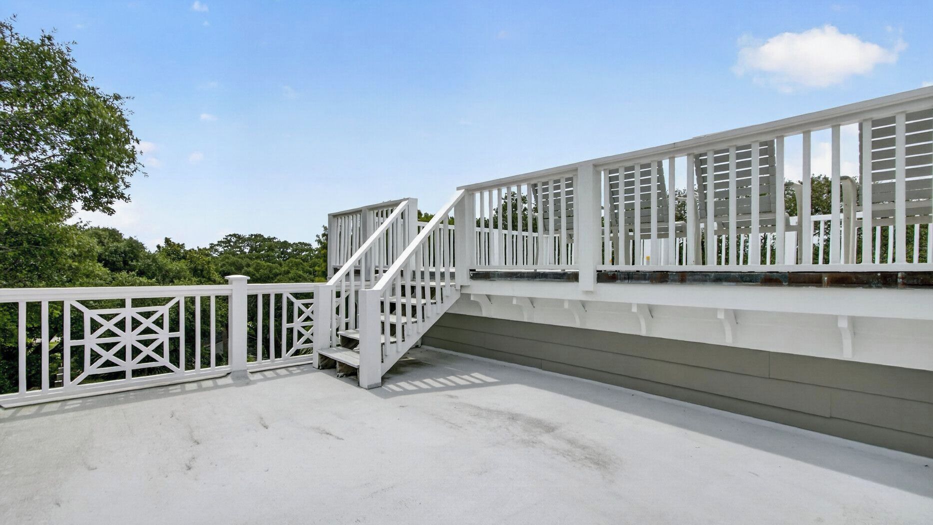 A white outdoor staircase leading to a deck with railings.