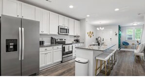 A modern kitchen with stainless steel appliances, white cabinetry, and a central island with bar stools.